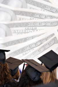 Graduates in their graduation caps and gowns with hundred dollar bill wallpaper in background