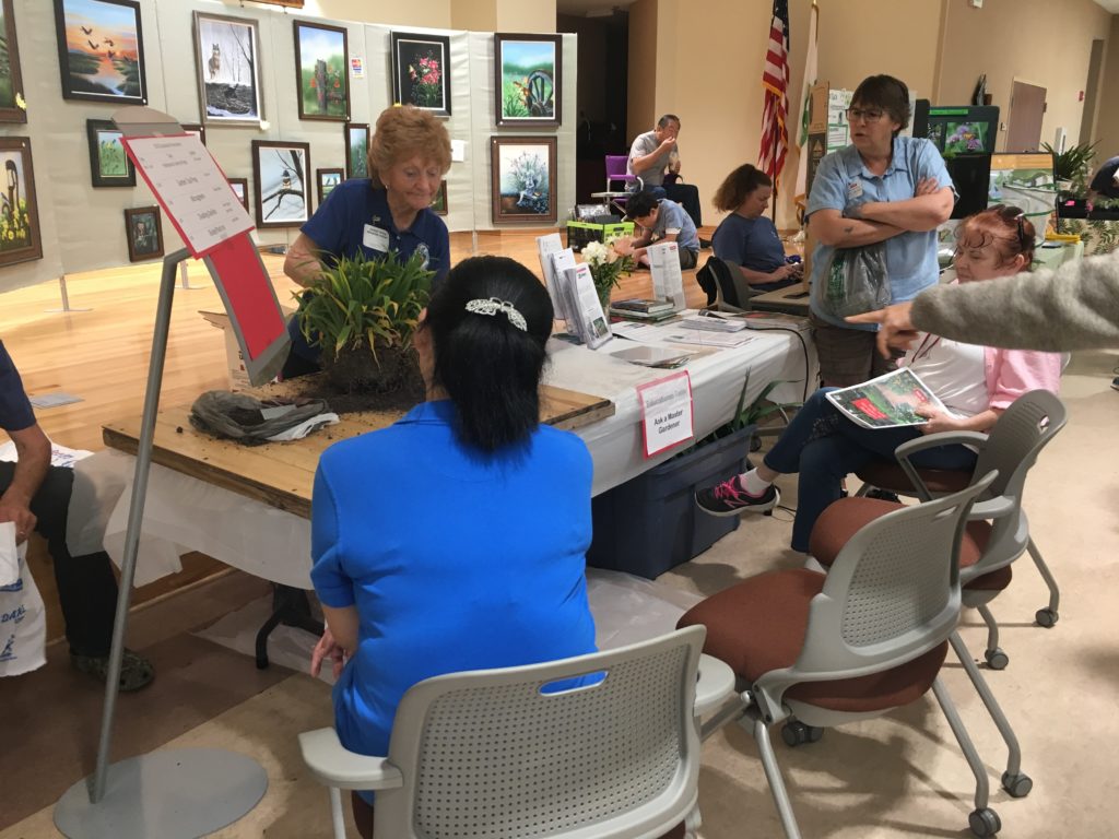 Master Gardeners at educational booth with plant