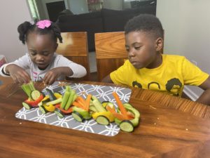 two young kids with train made out of vegetables