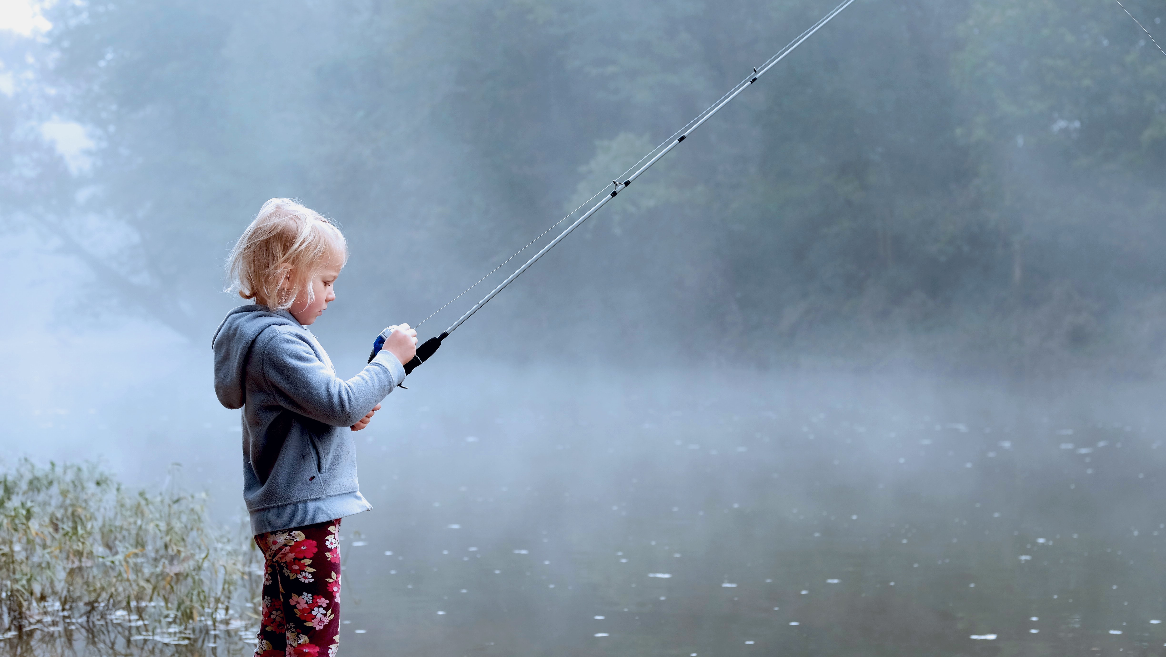 Child fishing on a foggy lake.